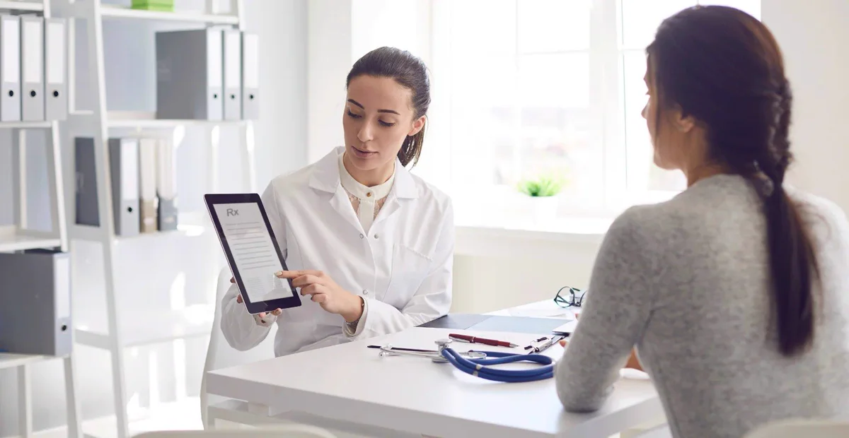 Clinic staff reviewing a patient consent form on a tablet in a modern consultation room